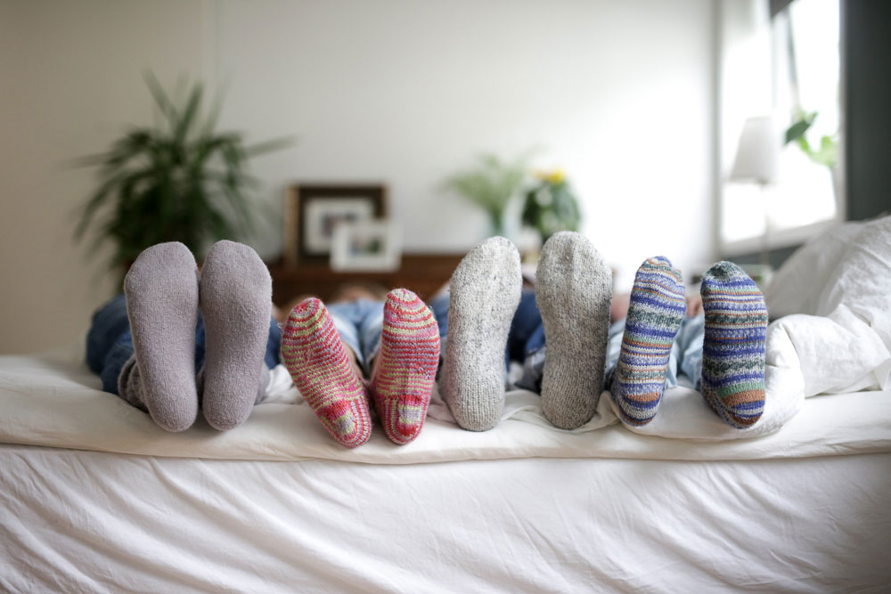 Føttene til en familie på fire med sokker på. Illustrerer at det er kaldt inne grunnet høye strømregninger.